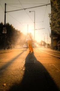 Girl walking down golden backlit street with long shadows (Tüdruk kõnnib vastu päikest tänaval, valguse ja varju kontrast)